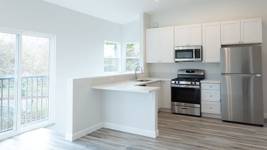Finished white kitchen with GE stainless appliances, quartz counters, and balcony slider.