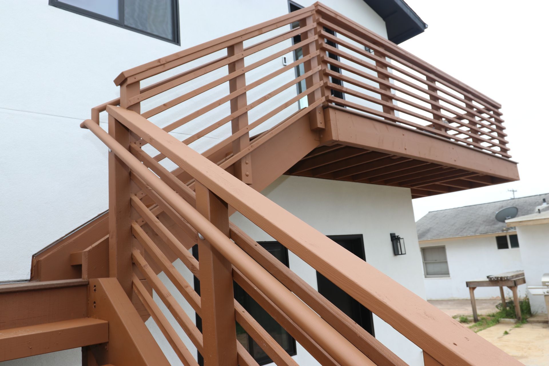 Exterior wood staircase and balcony railing on a two-story ADU.