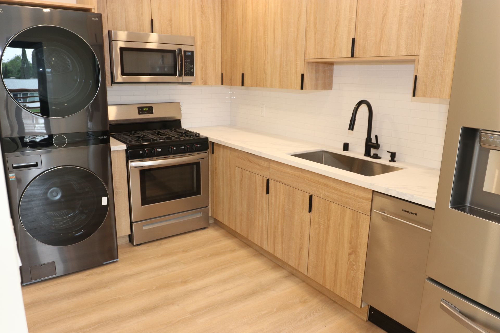 Oak cabinet kitchen with matte black faucet, white subway tile, and gas range.