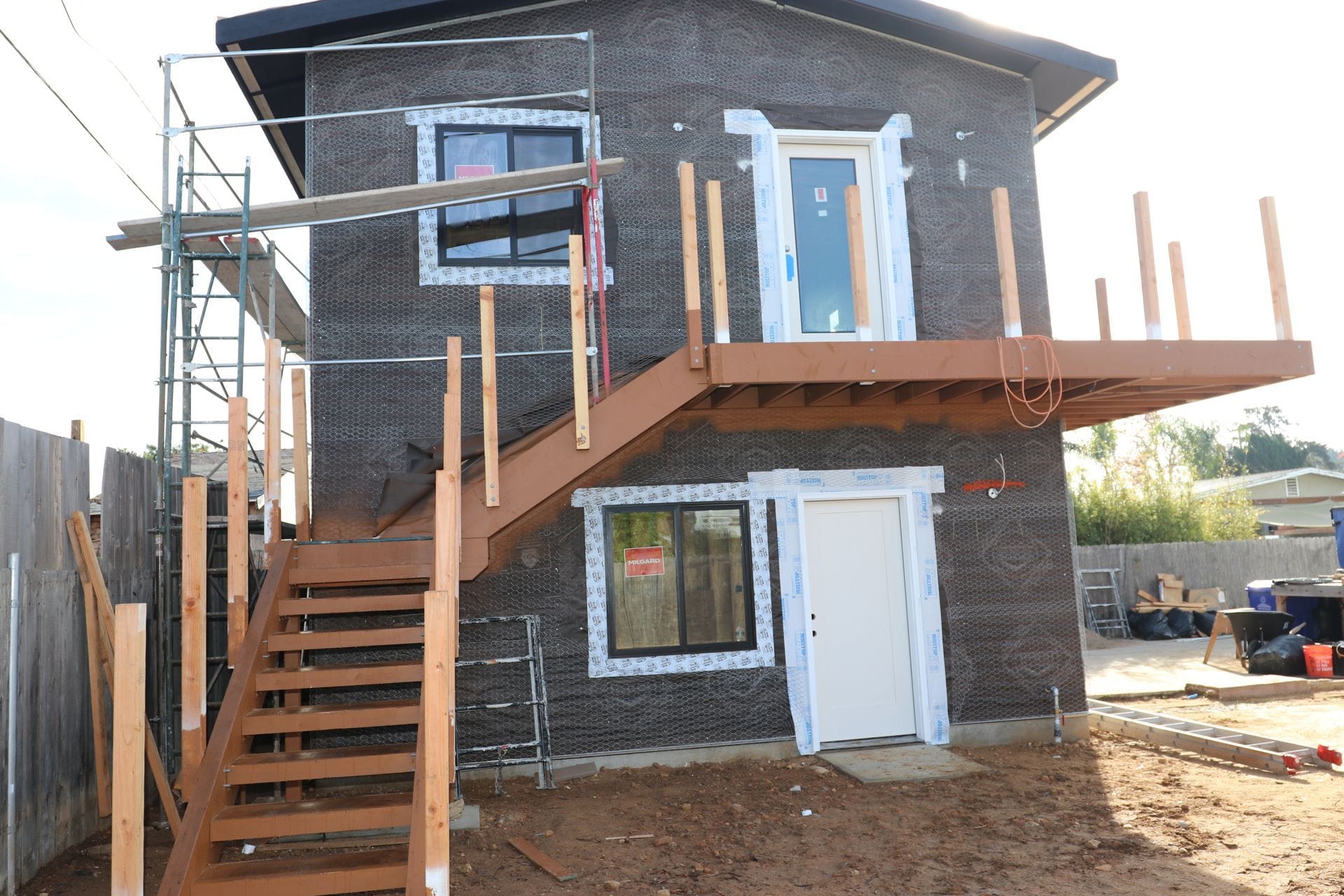Two-story ADU in progress showing exterior stair and balcony deck framing.