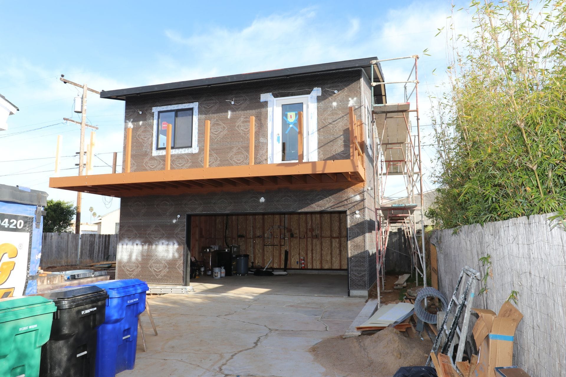 Two-story ADU over a garage under construction with weather wrap and scaffolding.